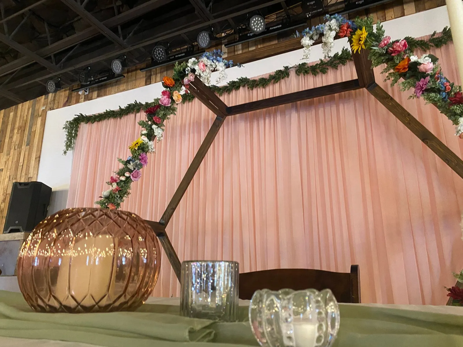 Event venue stage with a floral arch and candle centerpieces on the head table
